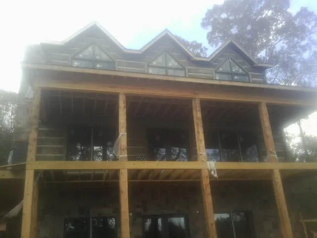 Dormers and porch framing on a large log home under construction — Roof Coating work by our crew in Tifton